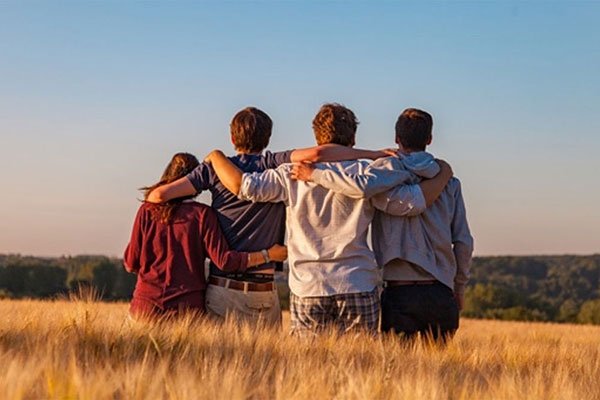four-young-people-arms-over-each-others-shoulders